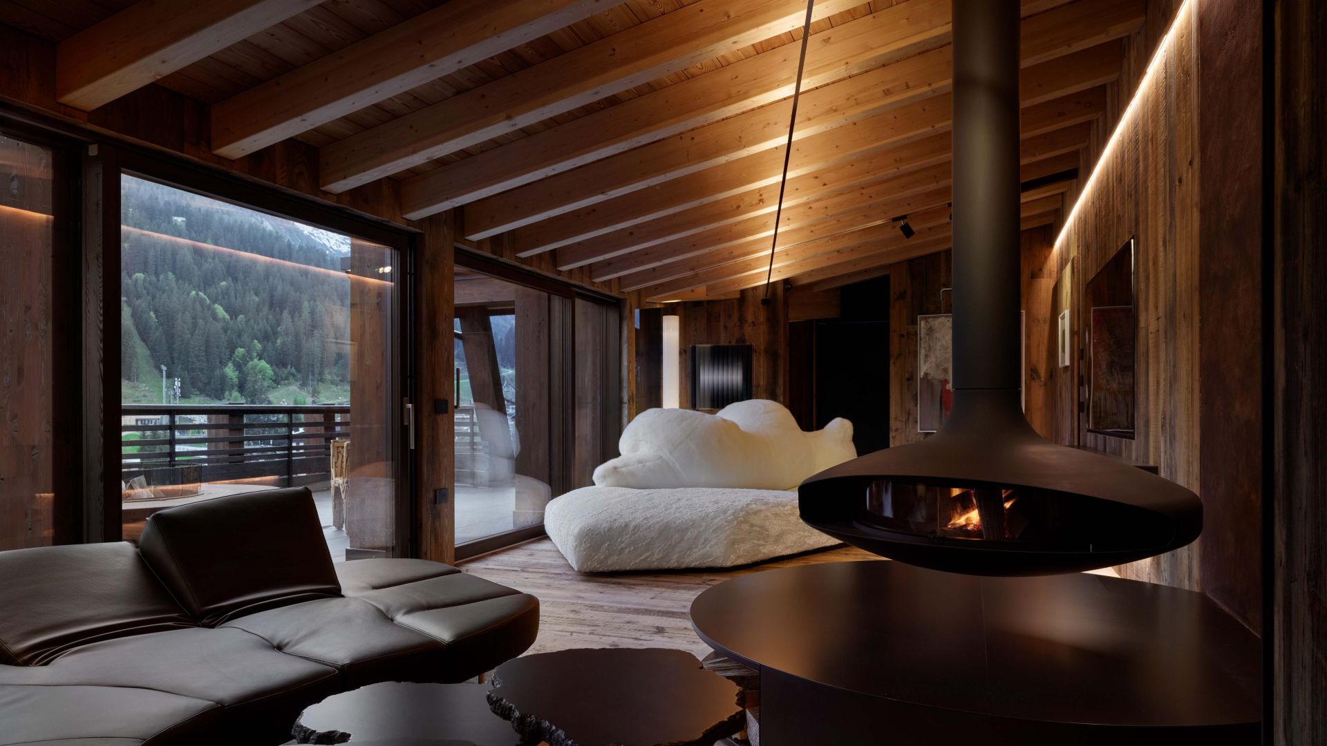   Pack ,  Flap  and  Cicladi . The sofas and tables furnish the living area developed around a large suspended sculpture-fireplace, offering a dual view of the interiors and the landscape. In the background, the Favela armchair on the terrace. 